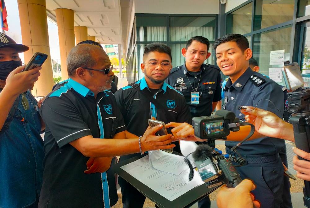 Hishamuddin (tengah) melihat Riza (kiri) menerangkan sesuatu kepada pihak Polis Diraja Malaysia (PDRM) berhubung hasrat MHO menyerahkan memorandum kepada Jabatan Audit Negara di Putrajaya pada Selasa.