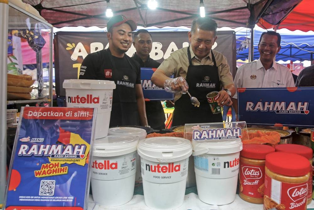 Salahuddin (dua, kanan) menunjukkan kemahiran membakar kuih apam balik yang dijual dengan harga Rahmah ketika melawat bazar Ramadan Bandar Prima Senawang. - Foto Bernama