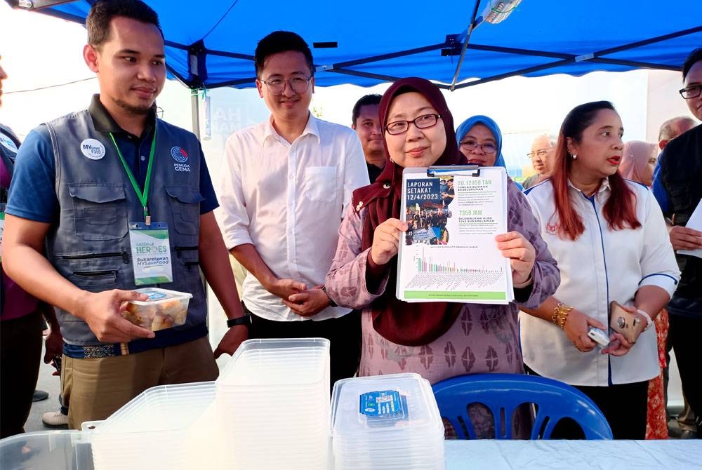 Fuziah (dua dari kanan) menunjukkan poster promosi MySaveFood Ramadan ketika hadir pada program itu di Bazar Ramadan Bandar Merlimau di sini lewat petang Rabu. - Foto Bernama