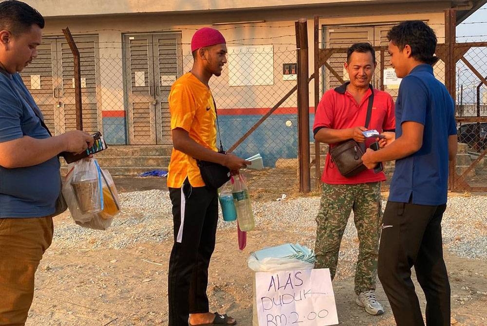 Mazlan (dua,kanan) tidak menang tangan melayan pengunjung yang ingin mendapatkan plastik alas untuk berbuka puasa di tepi Sungai Kelantan, Lembah Sireh, Kota Bharu.