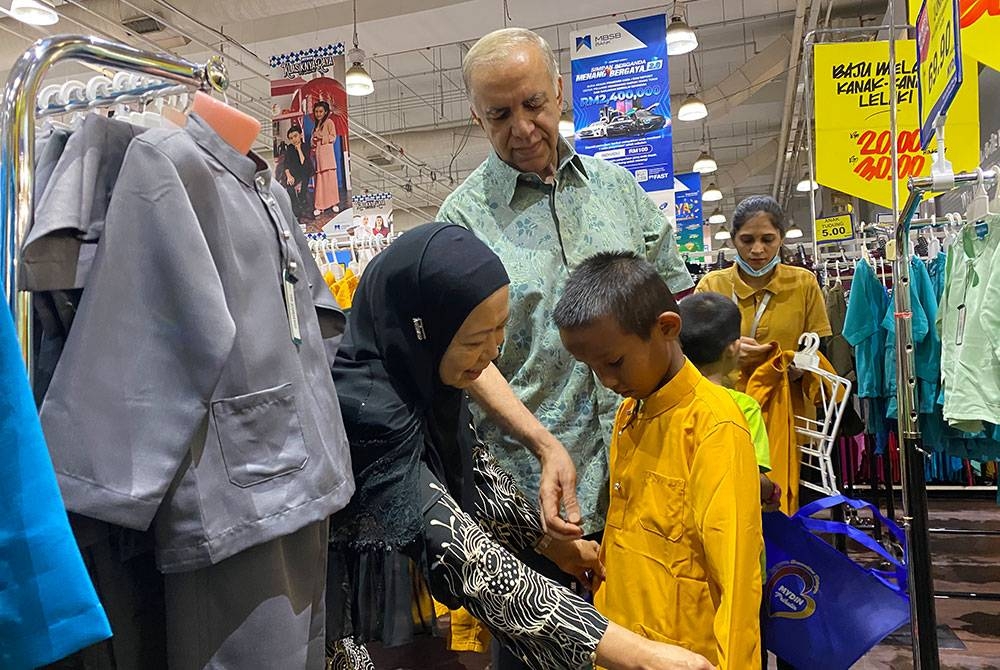 Ameer Ali bersama isteri, Siti Hawa memakaikan baju Melayu kepada salah seorang penghuni Rumah Jalinan Kasih