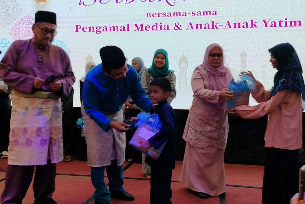 Saiful Zaini (dua dari kiri) menyampaikan sumbangan kepada anak yatim yang diraikan pada majlis berbuka puasa di sini pada Rabu.