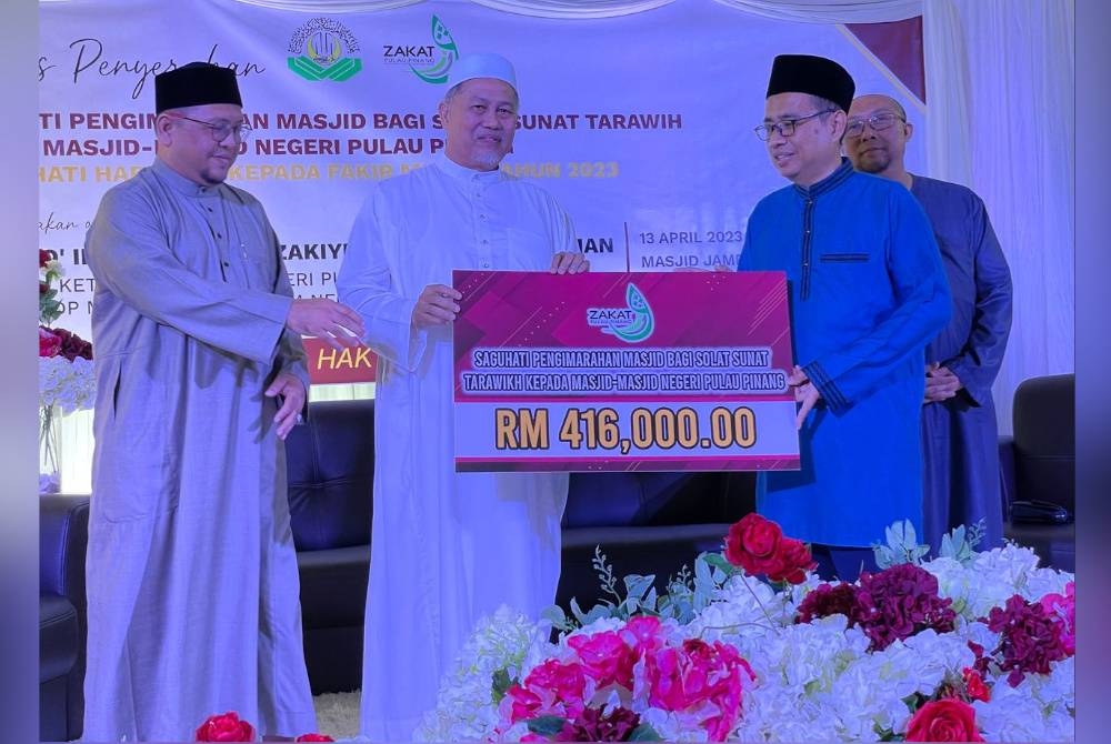 Dr Roslan (dua dari kiri) menyampaikan replika cek saguhati pengimarahan masjid bagi solat tarawih kepada Pegawai Tadbir Agama Daerah Seberang Perai Tengah, Mohamad Fazli Zain di Masjid Jamek Kubang Ulu, Bukit Mertajam sambil diperhatikan Amran (kiri).