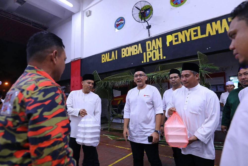 Nazirul (kanan) menyampaikan juadah sahur kepada anggota Balai Bomba dan Penyelamat Ipoh pada program Singgah Sahur Pemuda UMNO Perak di sini pada malam Khamis.