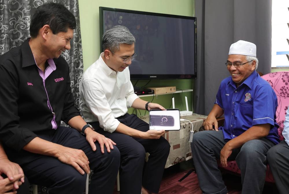 Fahmi melihat kelajuan jalur lebar TIME yang dilanggan oleh Abdul Rahim Ahmad (kanan) selepas Majlis Pelancaran Pakej Perpaduan PPR/ PA @ MyKabel di PPR Kerinchi pada Jumaat.
Turut hadir Pengarah Eksekutif TIME dotCom, Datuk Zainal Amanshah Zainal Arshad (kiri). - Foto Bernama