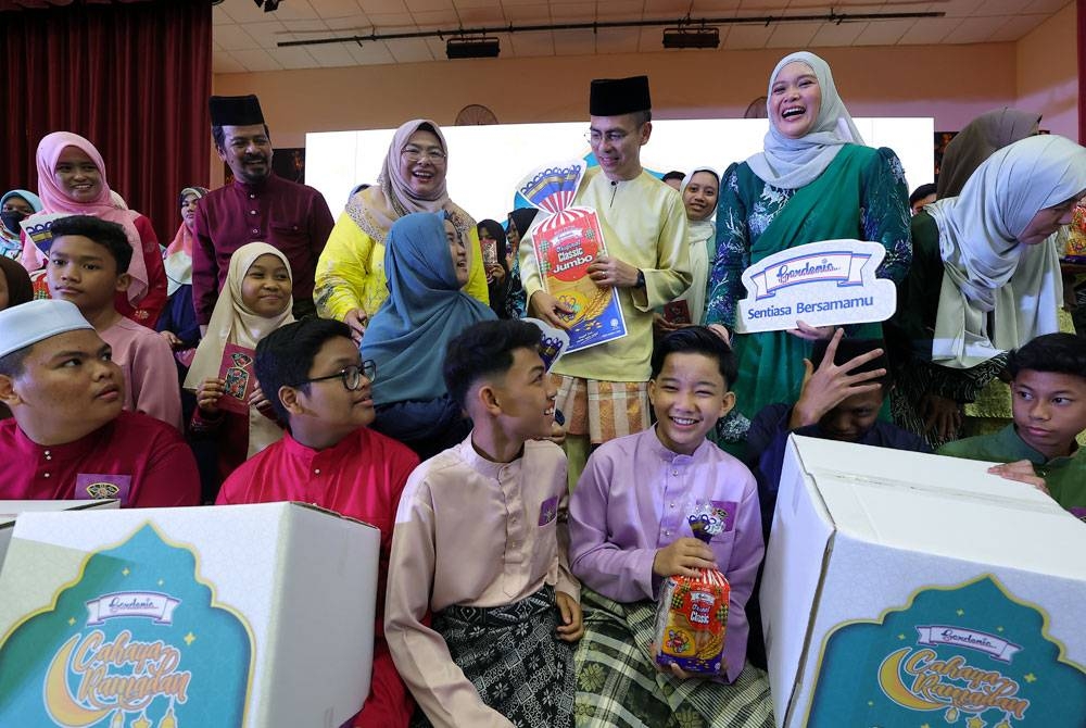 Fahmi beramah mesra bersama para penerima sumbangan Hari Raya ketika Majlis Berbuka Puasa pada Program Cahaya Ramadan bersama Gardenia di Sekolah Menengah Kebangsaan Seri Pantai malam ini. - Foto Bernama