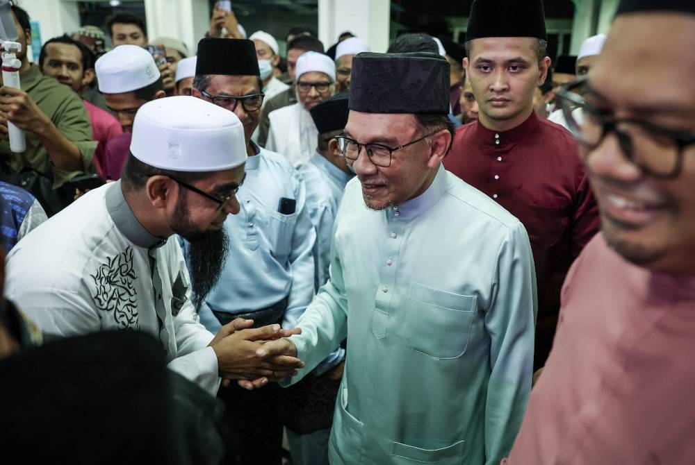 Anwar bersalaman dengan para jemaah ketika hadir ke Masjid Ibadurrahman bagi menunaikan solat Isyak dan solat sunat tarawih malam ini. - Foto Bernama