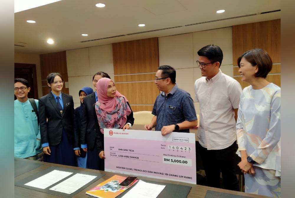 Lih Kang (tiga dari kanan) menyampaikan replika cek RM5,000 kepada Khairulniza pada Majlis Penyerahan Insentif Galakan MOSTI kepada SMK Seri Teja di Bangunan Perak Darul Ridzuan pada Jumaat.