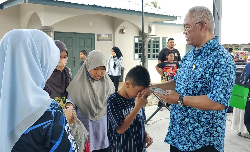 Noh (kanan) menyampaikan sumbangan kepada salah seorang penerima selepas Majlis Penyampaian Sumbangan Aidilfitri Anak Yatim Tanjong Karang di Dewan Terbuka Taman Seri Setia Tanjong Karang pada Ahad.
