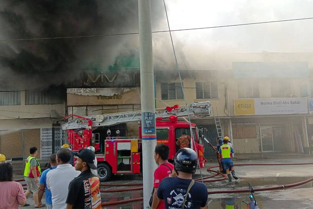 Pasukan bomba menjalankan operasi memadam kebakaran kedai telefon bimbit akibat dibakar suspek di Langkap pada Sabtu. - Foto Ihsan Pembaca