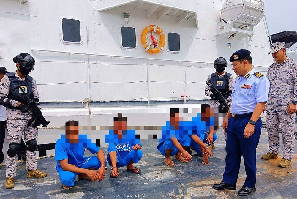 Syed Nor Adli (kanan) memeriksa empat nelayan asing Vietnam yang ditahan kerana menceroboh masuk perairan negara pada jarak 161 batu nautika dari Muara Tok Bali, Pasir Puteh pada Sabtu.