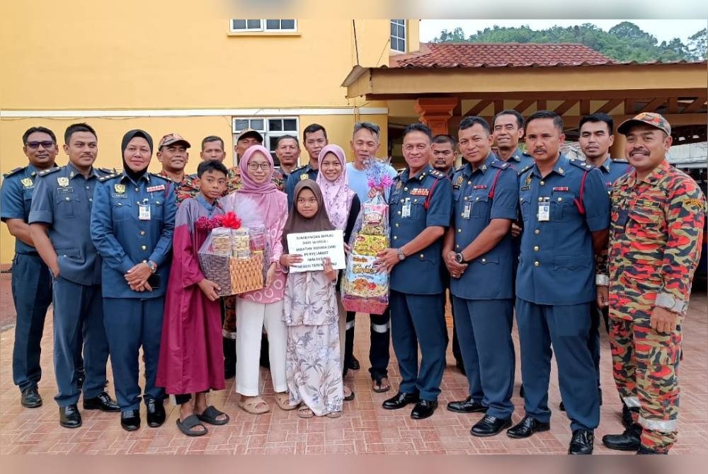 Hassan 'As'ari (empat dari kanan) menyerahkan sumbangan kepada enam beradik yatim piatu yang merupakan anak angkat bomba Terengganu di sini pada Isnin.