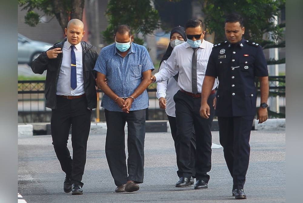 Gunasegaran (dua dari kiri) diiring polis sebaik tiba di mahkamah.