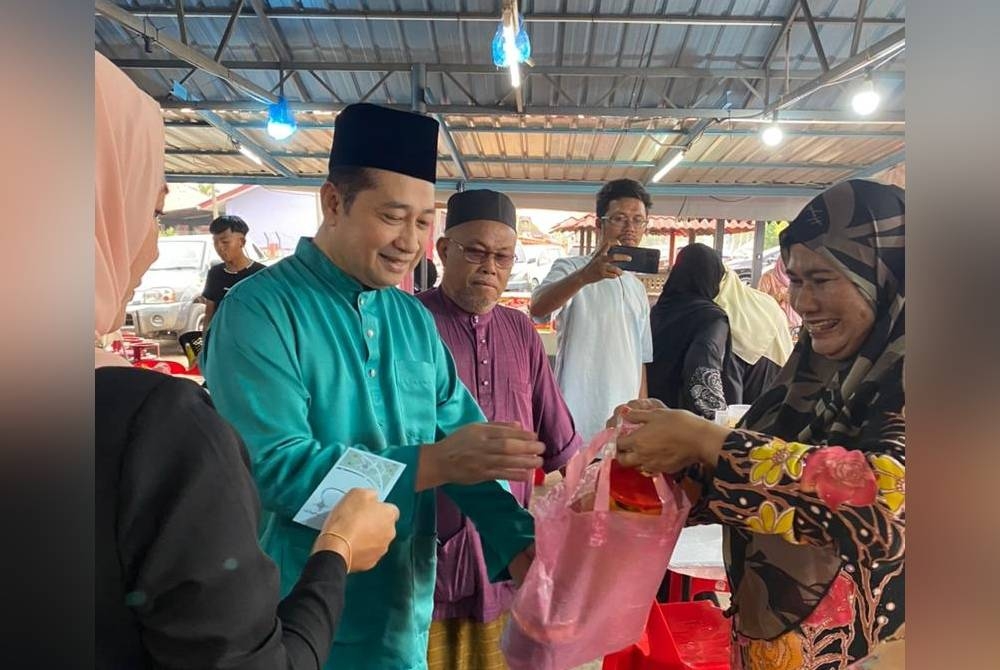 Datuk Amran Hussain (dua dari kiri) menyampaikan sumbangan kepada seorang penerima sempena majlis berbuka puasa dan sumbangan Hari Raya Aidilfitri di Kuala Besut, Terengganu.