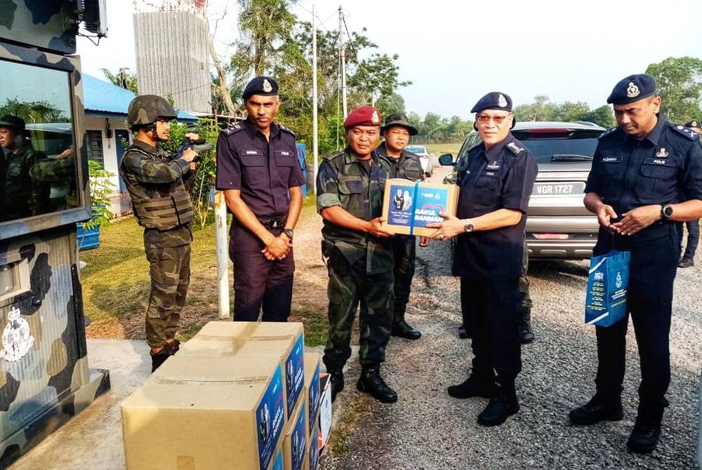 Wan Hassan (dua dari kanan) menyerahkan sumbangan Aidilfitri kepada petugas di Martak Bukit Kayu Hitam pada Rabu.