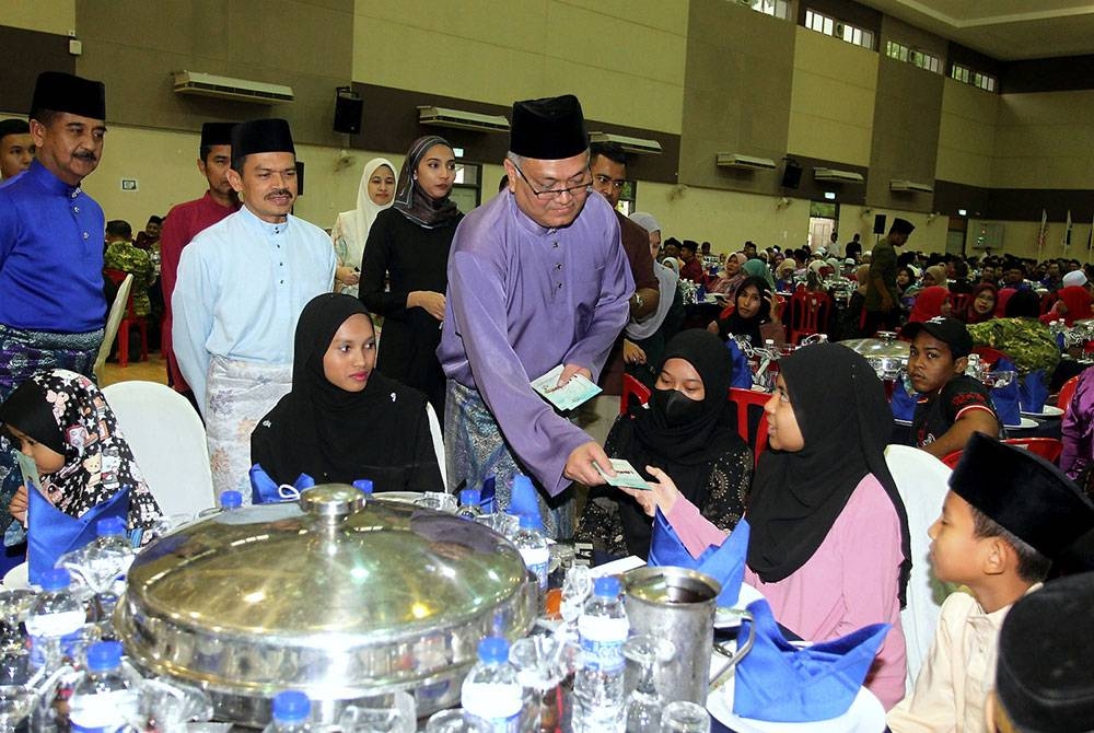 Shamsul Anuar (berdiri, tengah) menyampaikan duit raya kepada anak-anak yatim pada Majlis Penerapan Nilai-Nilai Murni dan Iftar KDN MADANI di Kolej Kemahiran Tinggi MARA Lenggong, pada Rabu. - Foto Bernama