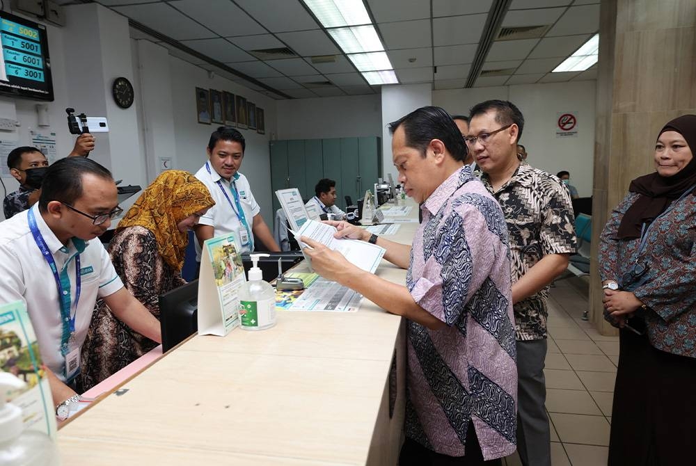 Ahmad (tiga dari kanan) melihat proses mengeluarkan wang STR kepada penerima yang layak pada program bersama pelanggan dan penerima STR di BSN Satok hari ini. Foto Bernama