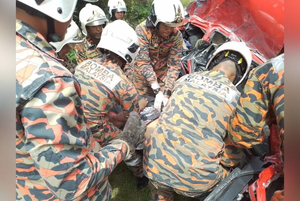 Anggota bomba berusaha mengeluarkan mangsa yang tersepit.