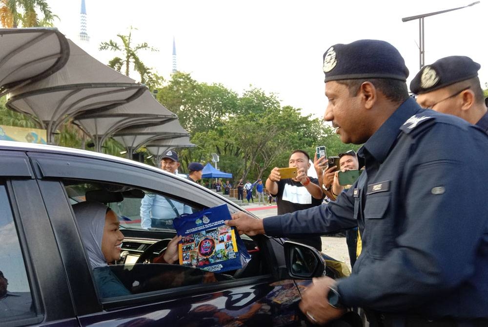 Hussein Omar Khan menyantuni pengguna jalan raya ketika Majlis Pelancaran Kempen Keselamatan Jalan Raya di Dataran Kemerdekaan Shah Alam pada Khamis.