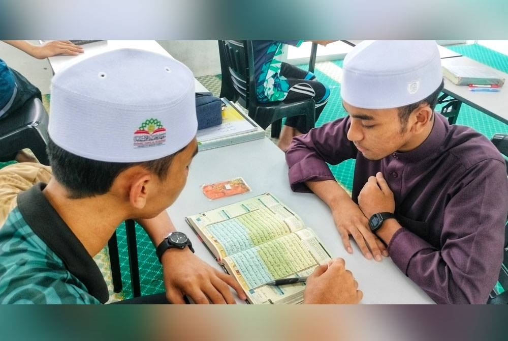 Muhammad Amir (kanan) yang juga Ketua Pelajar MTIS membantu rakan-rakan di maahad tersebut.