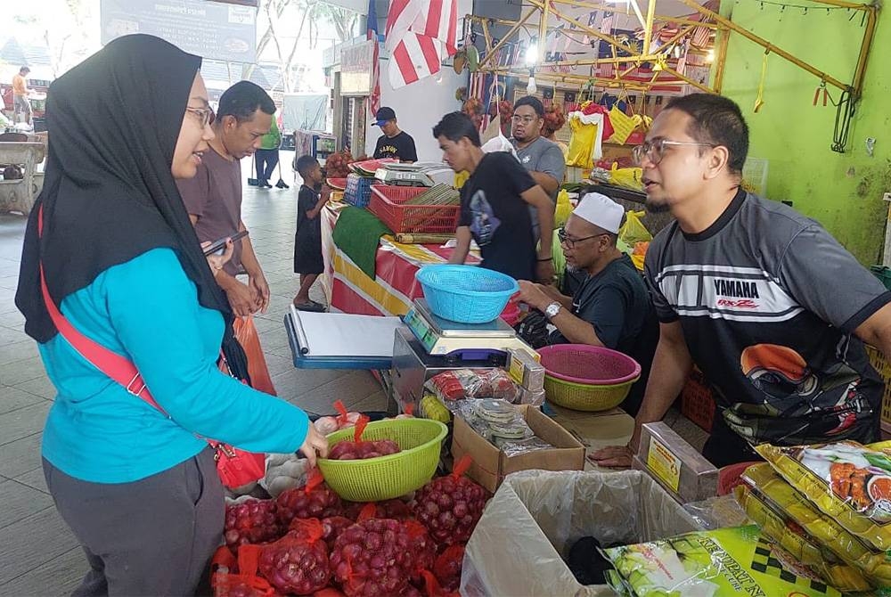 Wan Mohd Faqrurazi sedang melayan pelanggan di gerainya yang terletak di Pasar Seksyen 6.