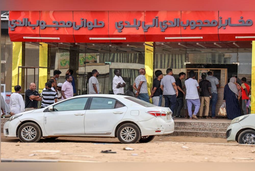 Orang ramai beratur untuk mendapatkan roti di luar kedai roti di Khartoum. - Foto AFP