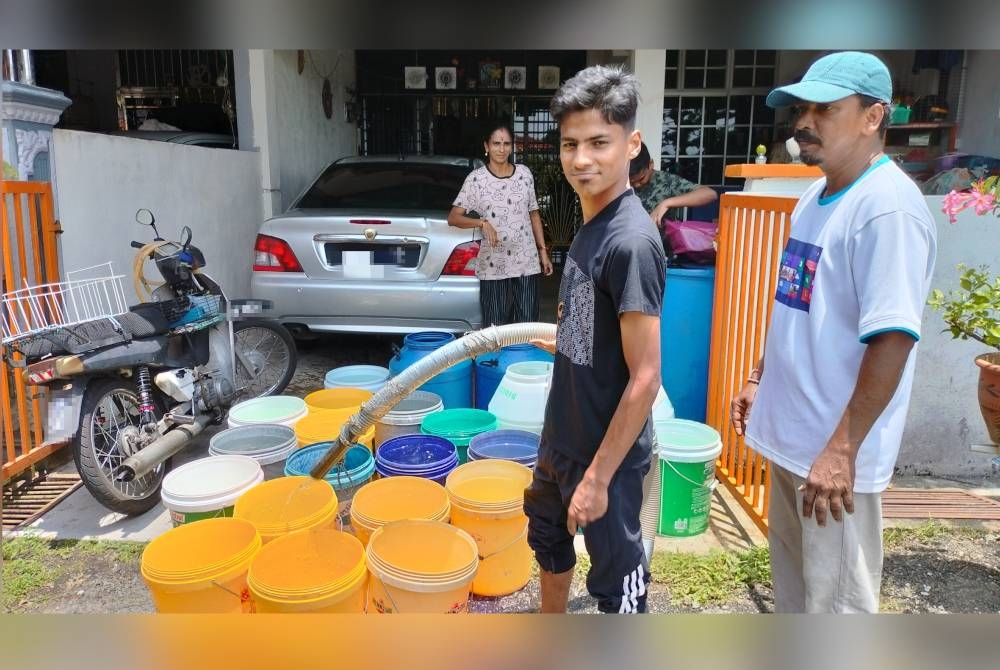 Shanker (kanan) menunggu Abdul Aziz menghantar bekalan air ke rumahnya di Taman Murni, Gurun.