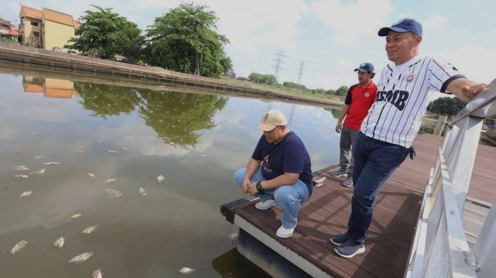 Rais (kiri) dan Shadan (dua,kiri) meninjau keadaan bangkai ikan yang timbul di Sungai Melaka pada Isnin.