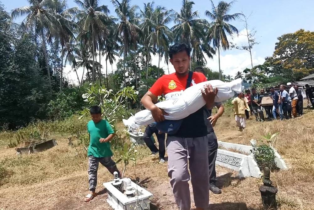 Muhammad Ubaidillah Zikri memangku jenazah anak sulungnya, Alisha Mardhiah ketika tiba di Tanah Perkuburan Padang Polis Batu Rakit, di Kuala Nerus pada Selasa.