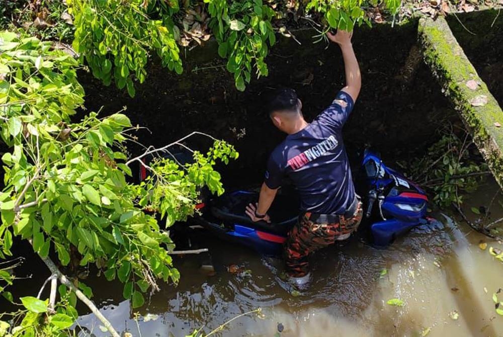 Anggota polis mengeluarkan seorang warga emas selepas motosikal ditunggangnya terbabas dan masuk longkang di Kilometer 12.2 Jalan Batu Ampat-Lukut Cina, Kota Tinggi pada Rabu.