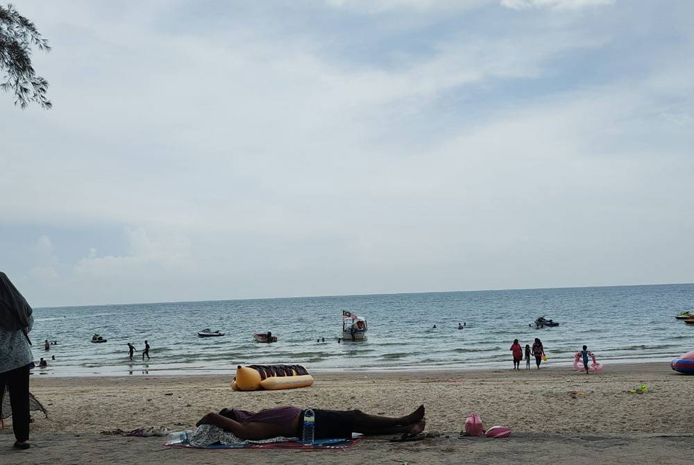 Orang ramai mandi manda di pantai Teluk Kemang sempena cuti Aidilfitri.