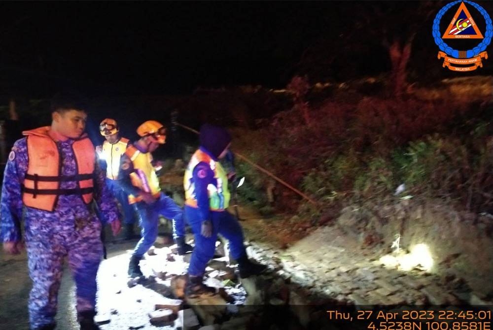 Pegawai dan anggota APM Beruas ke lokasi kejadian memantau keadaan tanah runtuh yang berlaku pada malam Khamis. Foto Ihsan APM