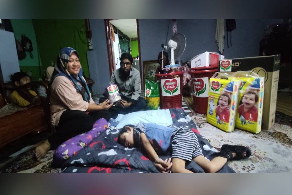 Devanathan (kanan) menyerahkan sumbangan Econsave Prihatin kepada Nurul Ain semasa menziarahi Muhammad Aqil Sudais di Kampung Pida 8, Tandop, Ayer Hitam baru-baru ini.