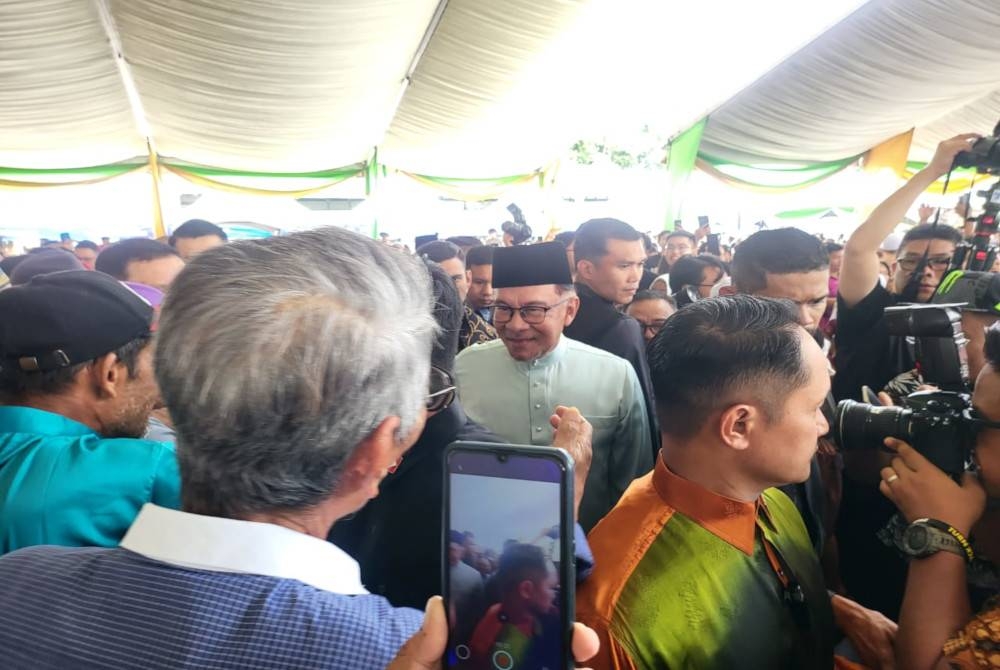 Anwar bersalaman dengan orang ramai sebaik tiba pada Majlis Rumah Terbuka Aidilfitri Kerajaan Negeri Sabah yang diadakan di SICC Kota Kinabalu.