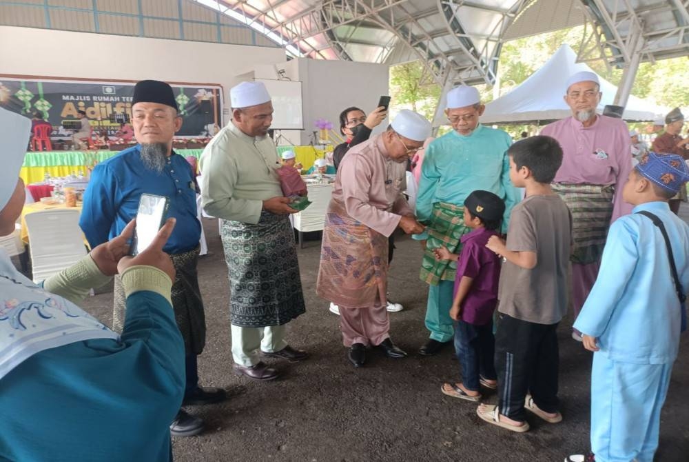 Idris menyampaikan duit raya kepada kanak-kanak yang hadir ke Majlis Rumah Terbuka Aidilfitri Peringkat Pas Perak di Arena Lawin, Pekan Lawin di sini pada Ahad.