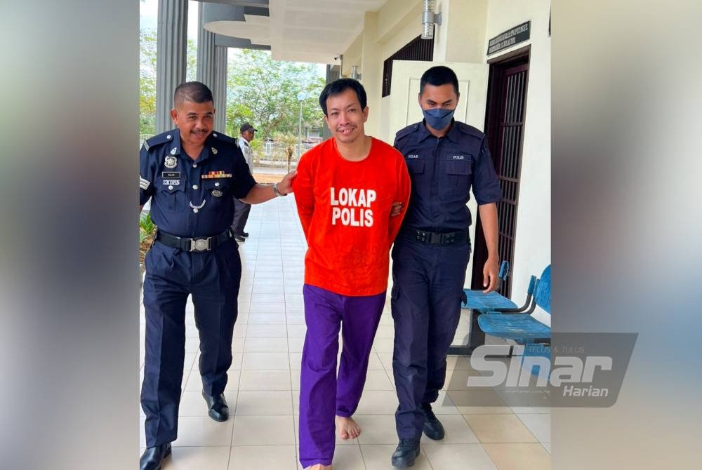 Kim San (tengah) dikawal polis keluar dari bilik Mahkamah Sesyen Pasir Mas pada Ahad.