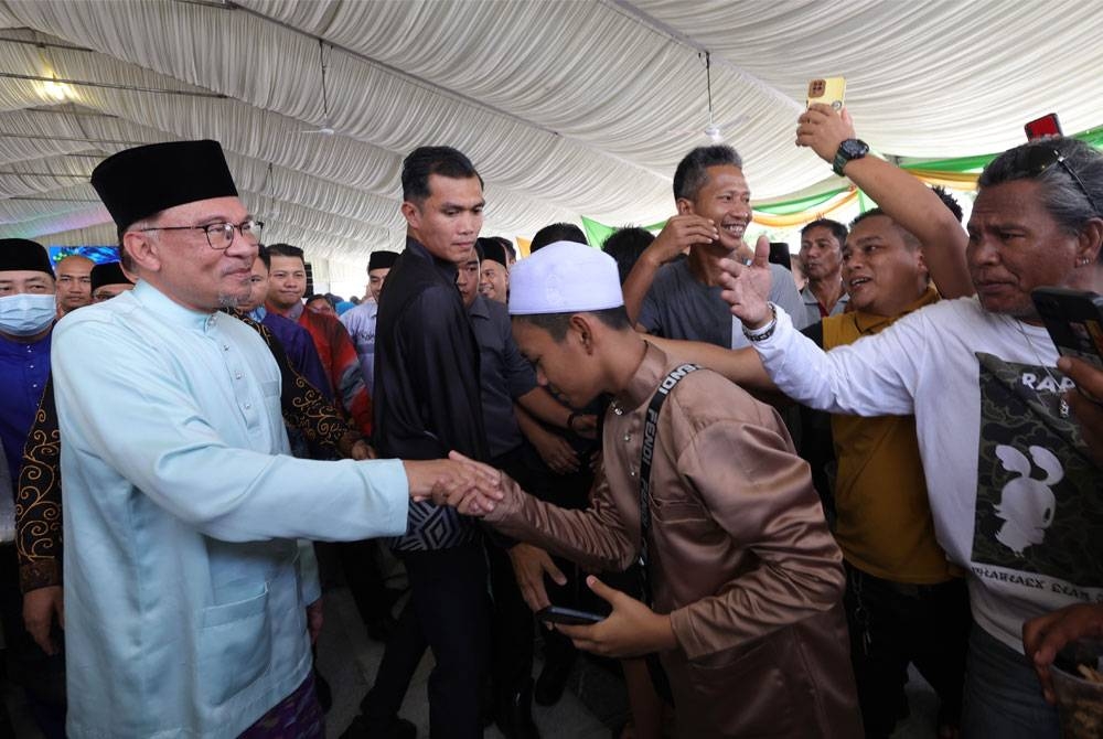 Anwar bersalaman dengan orang ramai ketika hadir pada Majlis Rumah Terbuka Aidilfitri Kerajaan Sabah pada Ahad. - Foto Bernama