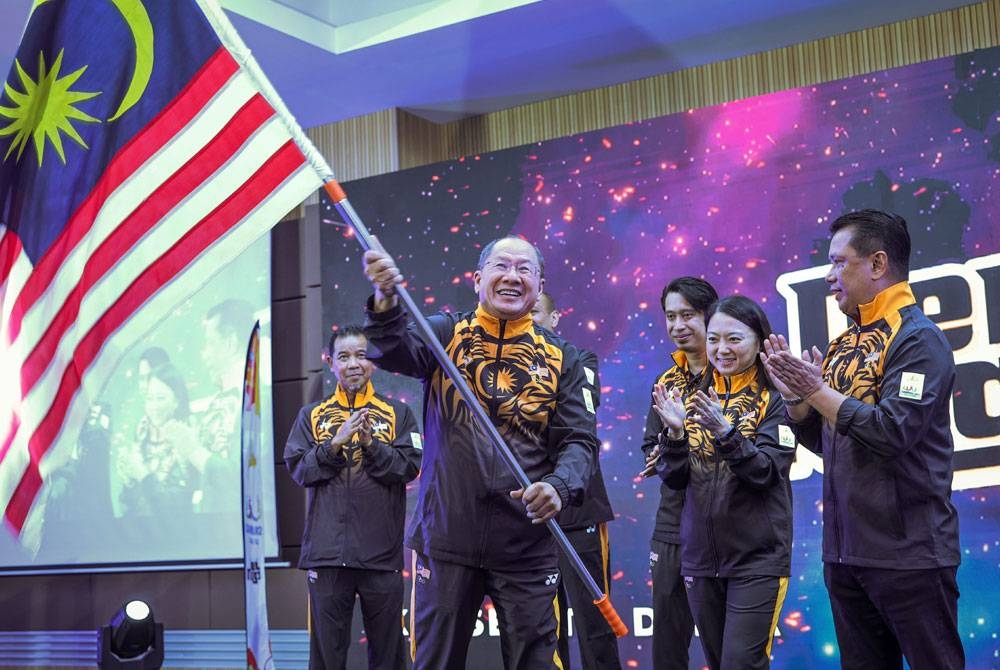 Ketua Kontinjen (CDM) Malaysia ke Sukan SEA Kemboja, Datuk Mohd Nasir Ali mengibarkan Jalur Gemilang yang diserahkan Hannah (dua dari kanan) pada Majlis Penyerahan Jalur Gemilang Kontinjen Malaysia ke Sukan SEA Kemboja 2023 di MSN, Bukit Jalil pada Ahad.