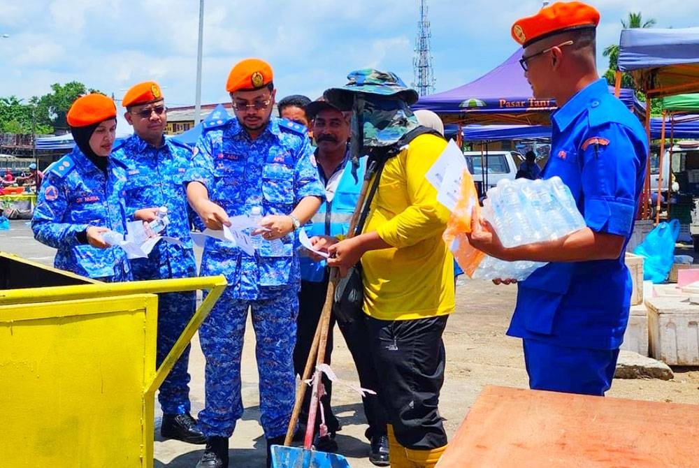 Dr Nurul Ain (kiri) dan Nik Saiful Adli (tiga dari kiri) agihkan air mineral percuma dan risalah kepada orang ramai di sekitar Melor, Kota Bharu.