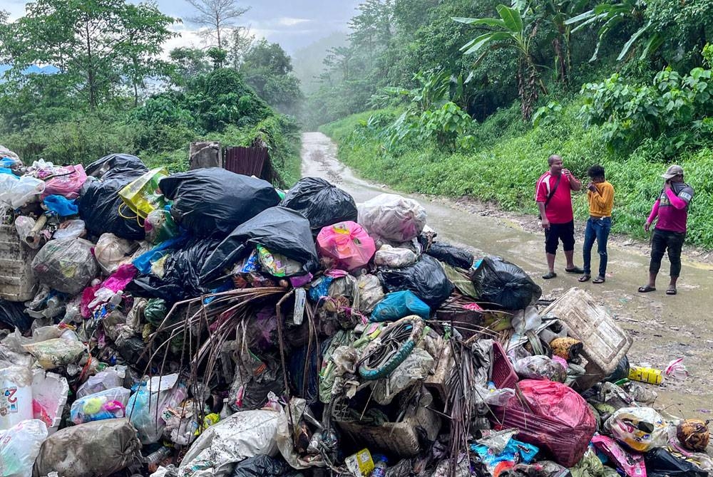 Penduduk Orang Asli terpaksa menutup hidung ketika melalui jalan utama ke penempatan Orang Asli Kampung Pasir Linggi, Pos Lebir berikutan longgokan sampah yang tidak diselenggara dengan baik ketika tinjauan di sini. - Foto Bernama