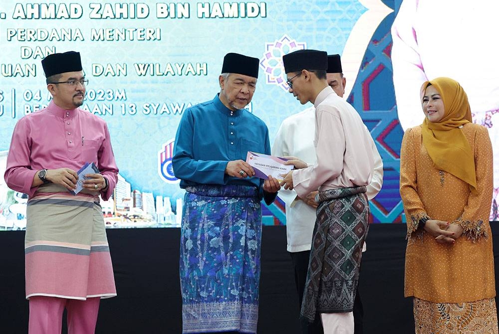 Ahmad Zahid (dua, kiri) menyampaikan sumbangan kepada pelajar Maktab Sains Mara (MRSM) Kota Kinabalu ketika melakukan lawatan di MRSM itu hari ini. Foto Bernama