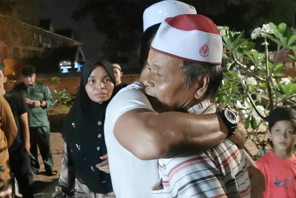 Harun dipeluk ahli keluarga selepas urusan pengebumian jenazah dua anaknya di Tanah Perkhuburan Islam Bukit Tunggal di Kuala Nerus selesai kira-kira jam 11.15 malam pada Jumaat.