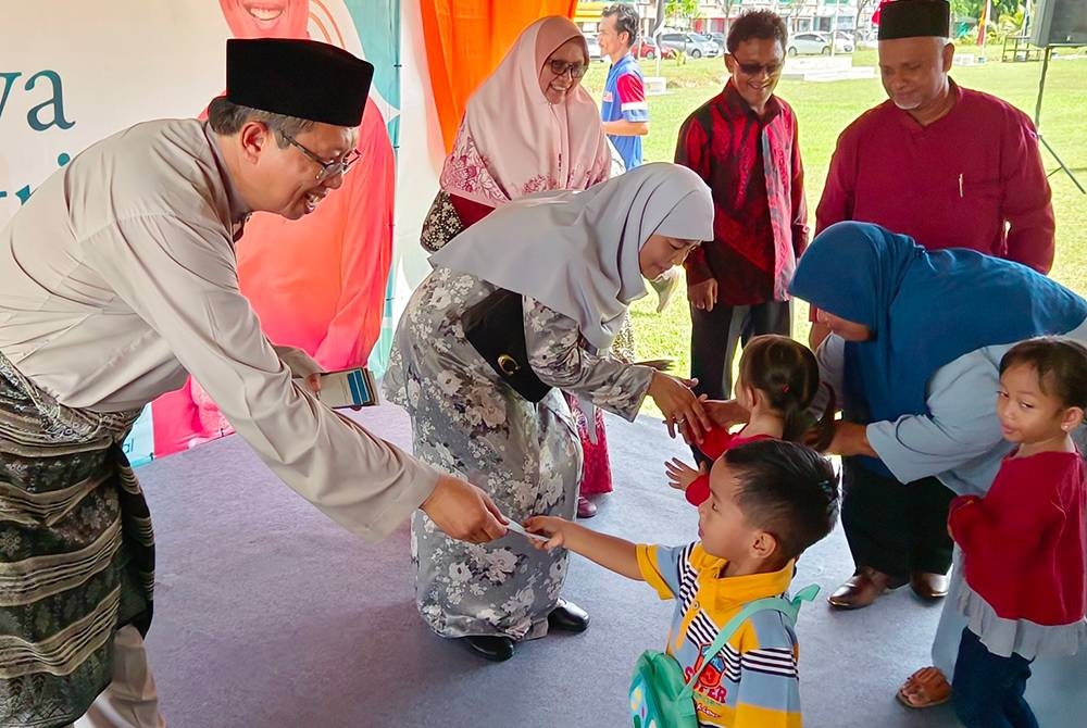 Mohammad Nizar menyampaikan duit raya kepada kanak-kanak yang hadir pada Majlis Sambutan Hari Raya Aidilfitri ADUN Sungai Rapat di Taman Lapangan Jaya di Ipoh.