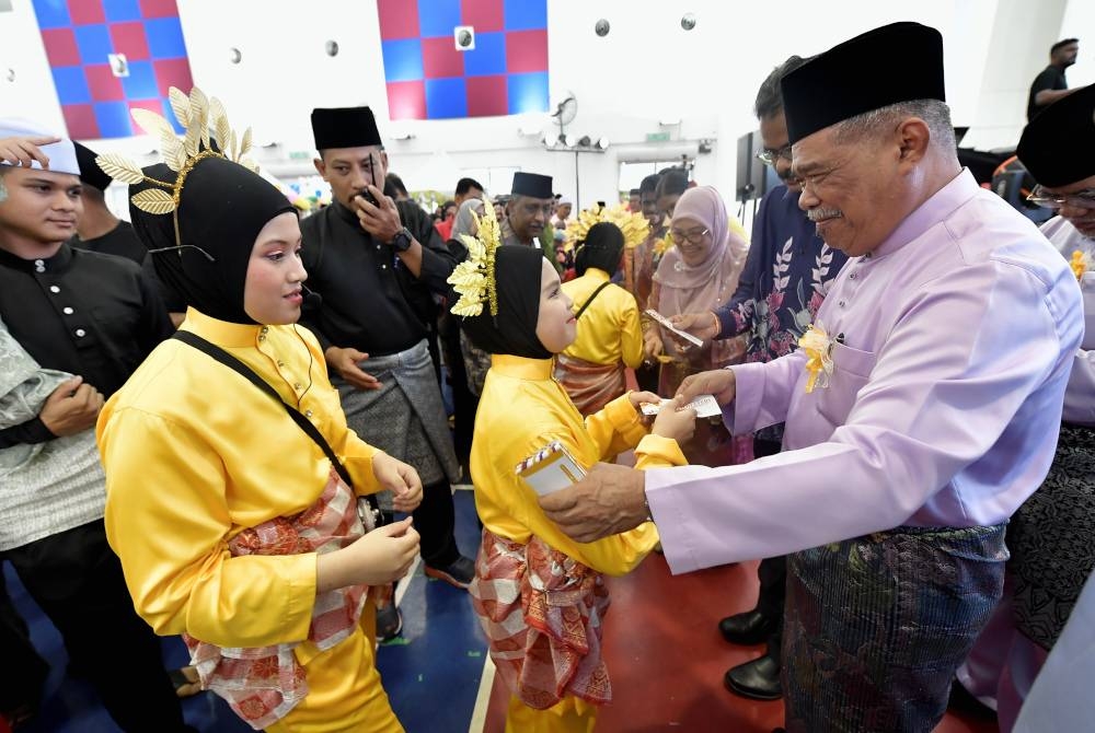 Mohamad (kanan) menyampaikan sumbangan duit raya pada Majlis Rumah Terbuka Aidilfitri Parlimen Kota Raja di Dewan MBSA Kota Kemuning Utama, pada Sabtu. - Foto Bernama