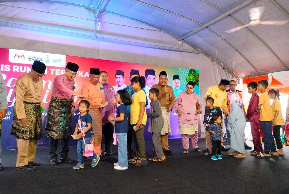 Mohamad (empat dari kiri) bersama pimpinan Amanah menyampaikan duit raya kepada kanak-kanak pada Majlis Rumah Terbuka Aidilfitri Amanah di Bayan Lepas, pada Ahad.