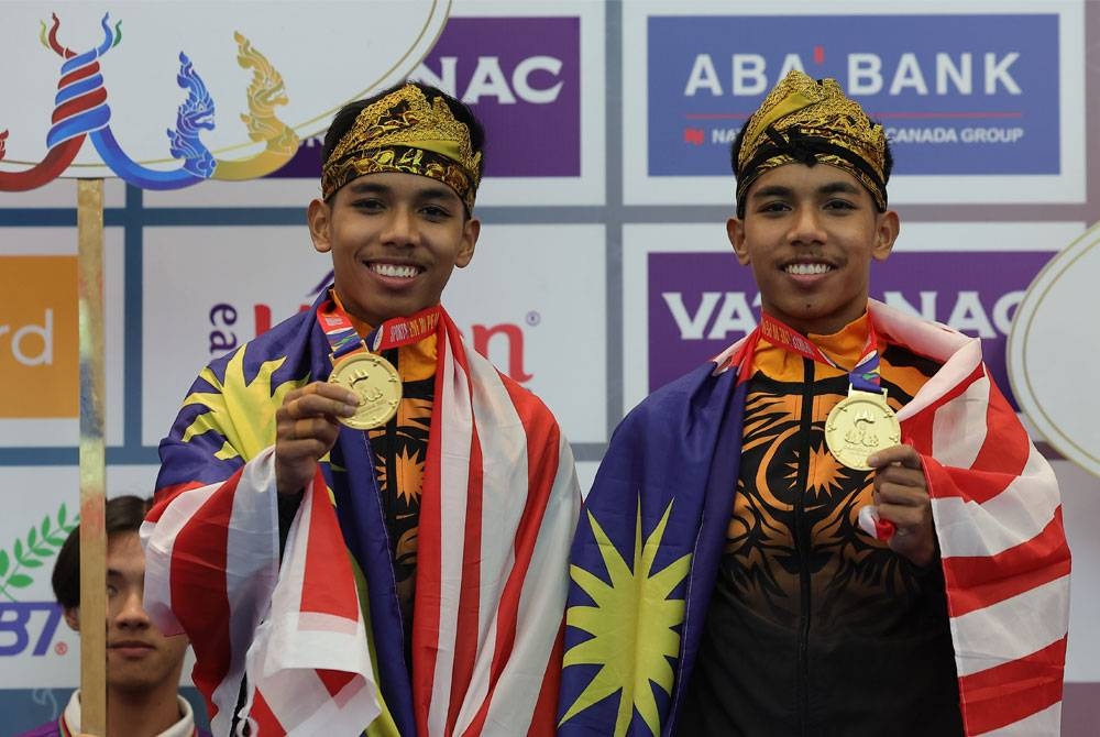 Muhammad Danial Azrol (kanan) dan Muhammad Danial Azray menunjukkan pingat emas dimenangi dalam acara silat seni ganda pada Sukan SEA 2023 di Pusat Konveksyen Chroy Changvar pada Ahad.