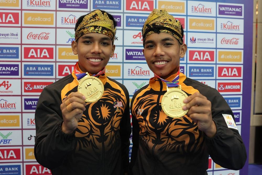 Pesilat negara yang juga pasangan kembar Muhammad Danial Azrol Noorazizan (kanan) dan Muhammad Danial Azray Noorazizan menunjukkan pingat emas yang dimenangi dalam acara Silat Seni Ganda pada Sukan SEA 2023. - Foto: Bernama 