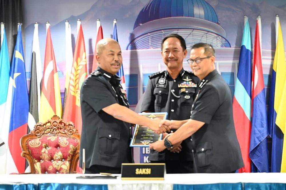 Jauteh (tengah) menyaksikan serah terima tugas antara Sapii dan Azmi bagi jawatan Ketua Jabatan Siasatan Jenayah Kontinjen Sabah di IPK Sabah, Kota Kinabalu.