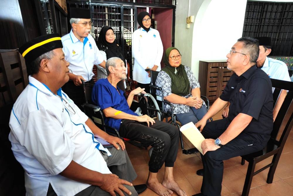 Adly (depan) melawat Zakaria (dua dari kiri) dan Asiah (dua dari kanan) di rumah mereka di Taman desa Rhu di Sikamat.