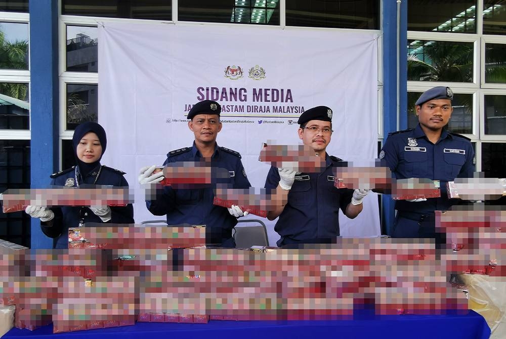 Mohd Nadzri (dua dari kanan) menunjukkan antara rokok yang dirampas dalam serbuan dilakukan Jabatan Kastam Diraja Malaydia (JKDM) Terengganu di Kampung Pengkalan Gelap, Setiu pada Sabtu lalu.